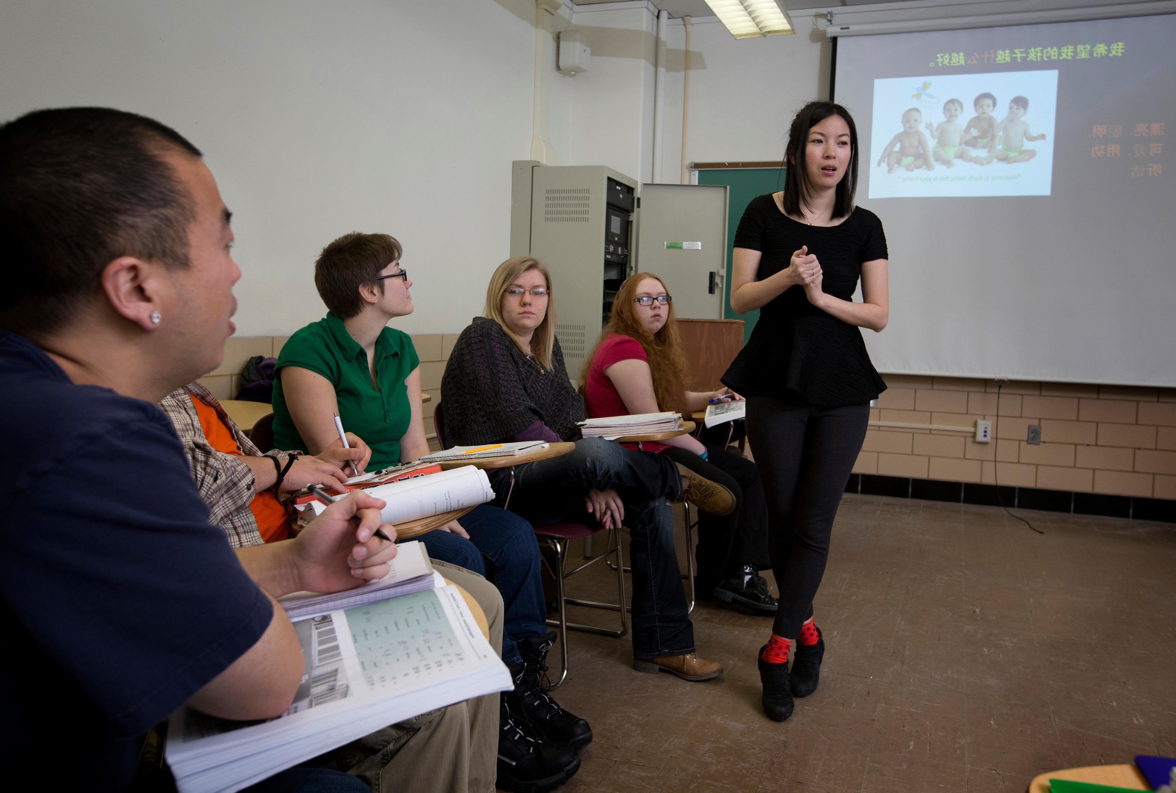 一群波士顿州立大学的学生坐在课桌前专心听教授讲课